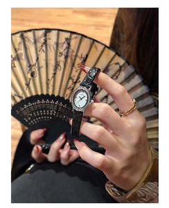 Detail of vintage oval watch with rhinestone bezel and black leather embossed strap