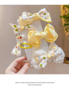 Detailed view of four colorful polka dot bow hair clips in yellow and white ribbon