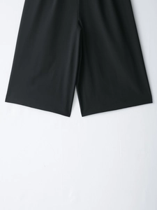 Détail d'un short noir à jambes larges montrant le tissu lisse et la coupe de qualité
