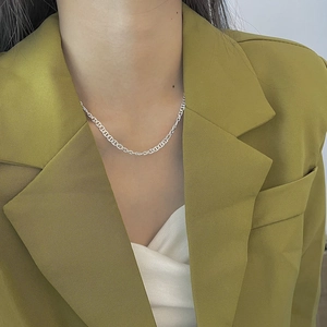 Close-up of a 925 sterling silver anchor chain necklace worn by a model in a green suit