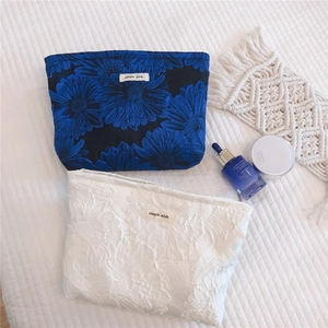 Close-up of floral jacquard cosmetic bags with simple wish labels and beauty products