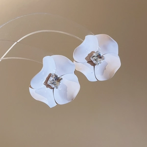 Detailed macro view of white floral stud earrings with crystal center and matte petals