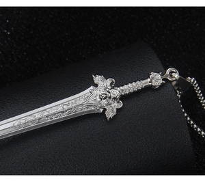 Macro shot of silver lion king sword pendant featuring intricate relief carvings on the blade