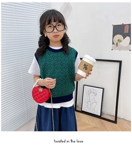 Detail of red heart-shaped quilted chain bag with pearl handle worn by child model