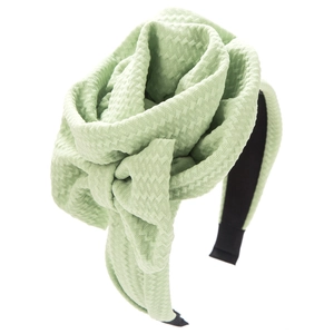 Close-up of light green knitted headband with large 3D flower and diamond pattern