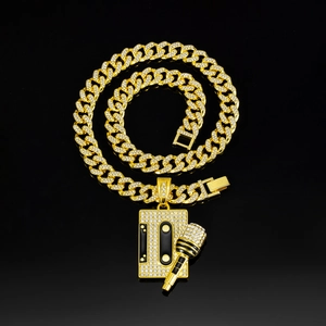 Detail shot of a gold-plated Cuban chain necklace with iced-out cassette and microphone charms