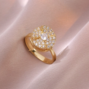 Eleganter goldener Drehring mit Zirkonia-Pflasterung auf rosa Seidenhintergrund
