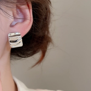 Silver square metal earring with ripple texture shown on ear for a modern style