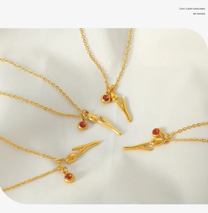 Detailed view of 18k gold plated tulip necklace with red crystal on white silk background