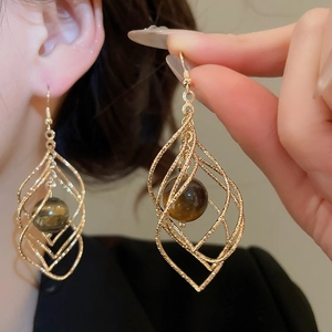 Detail showing twisted rhombus tiger eye stone drop earrings in elegant gold finish