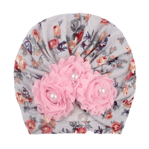 Detail of grey baby turban hat featuring pink fabric flowers and pearl center beads