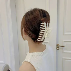 Detailed view of a creamy white butterfly hair claw clip securing a sleek bun hairstyle