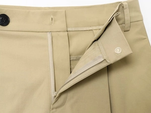 Dettaglio ravvicinato dei pantaloni casual kaki con patta a zip e chiusura a bottone