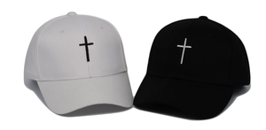 Close-up of black and white baseball caps featuring detailed cross embroidery on cotton