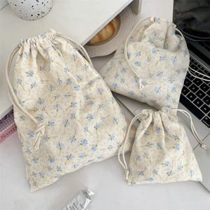 Three sizes of floral corduroy drawstring bags arranged on a stylish wooden desk