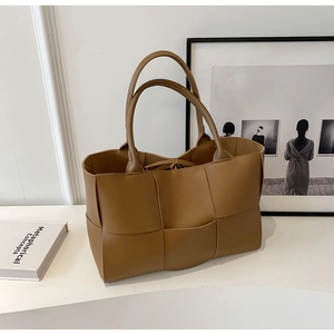 Detailed view of brown woven tote bag texture with elegant handle on minimalist background
