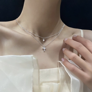 Detail of silver double layer necklace featuring cross and teardrop zircon pendants