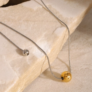Detail of mixed-tone gold and silver bead pendants on a stainless steel snake chain