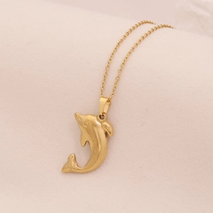 Makroaufnahme eines goldenen Delfin-Anhängers mit glänzender Metallkette im Detail