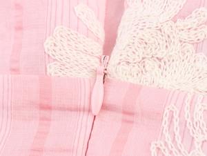 Detail eines unsichtbaren Reißverschlusses und beiger Spitzenstickerei am rosa Kleid