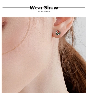 Close-up of a festive Christmas wreath earring with red bow on a model's ear