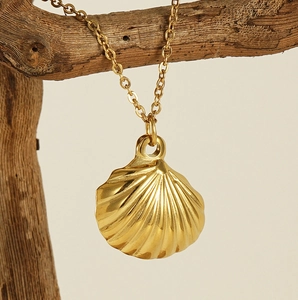 Detailed view of a gold shell pendant with textured ridges hanging on a wooden branch
