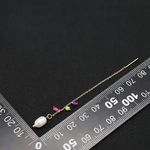Baroque natural pearl drop earrings with long gold threader chain shown on scale