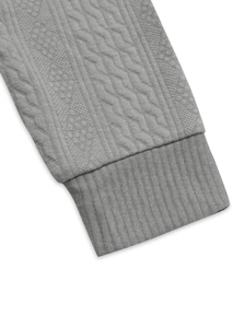Detailed view of grey knit sweater cuff with ribbing and cable texture patterns