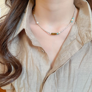 Detail of beaded necklace with tiger eye stone, pearls and turquoise on a model