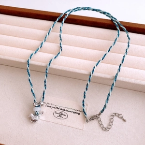 Détail du cordon tressé bleu fait main avec pendentif oiseau et perle sur support velours
