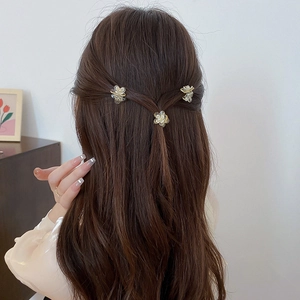 Three cute cream yellow floral hair clips with pearls styled on a woman's hair
