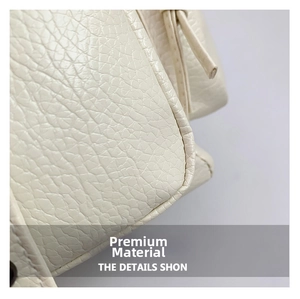 Close-up of premium white litchi grain leather texture and detailed stitching on backpack