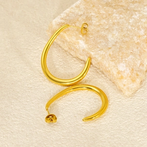 Close-up of polished 18k gold plated C-shaped earrings on elegant stone display