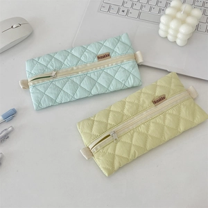Detail of quilted nylon stationery bags in mint and yellow with smooth zipper and woven strap