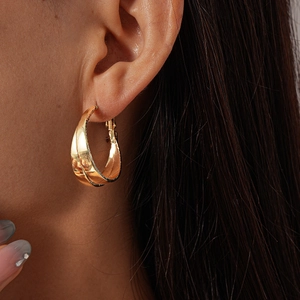 Close-up of elegant gold twisted double-layer hoop earrings worn by a model