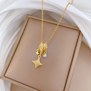 Gold titanium star necklace with pearls and crystals on a beige jewelry box backdrop