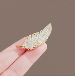 Detailed shot of a gorgeous gold feather brooch, sparkling crystal paved accessory for suit.