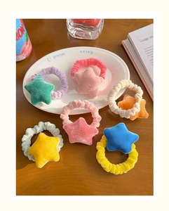 Close-up of six colorful plush star hair ties with velvet texture on a table