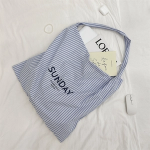 Detail of blue striped canvas tote bag with SUNDAY print on a white fabric background