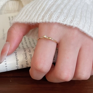 Detailed view of elegant golden bow-shaped open ring on finger with cozy aesthetic