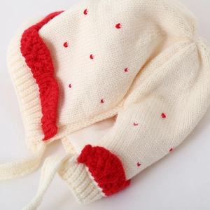 Detail van gebreide babymuts met rode stippen en een fijne zachte gebreide textuur