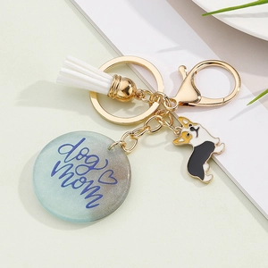 Detail of Dog Mom resin pendant with corgi charm and white tassel on gold keychain