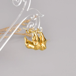 Golden irregular molten lava earrings displayed on a crystal clear jewelry stand