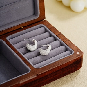 Modern frosted silver C-shaped stud earrings in a luxury jewelry box with velvet lining
