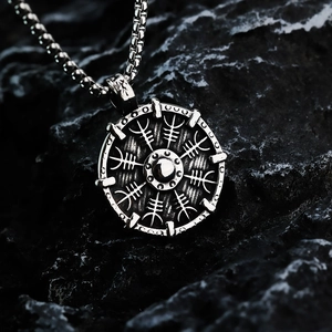 Nordic Viking compass necklace with silver shield pendant on dark rock background