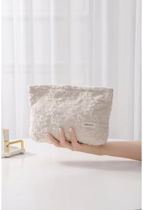 Detail of beige corduroy makeup bag featuring delicate lace flower embroidery