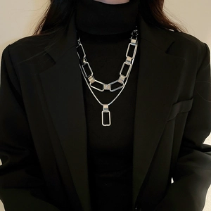 Close-up of double-layer silver chain necklace with rectangular links and pendant on model