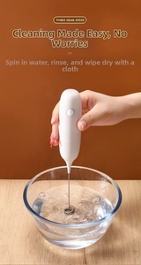 Close-up of handheld electric milk frother self-cleaning in water with 3-speed control
