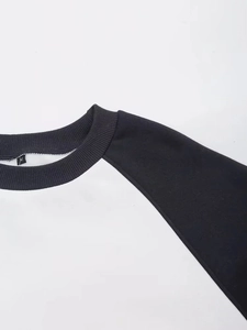 Close-up of raglan sleeve detail and black crew neck collar on a white sweatshirt