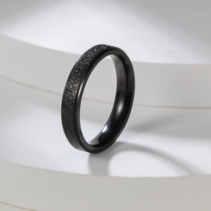 Detailed macro view of black matte frosted stainless steel ring on geometric pedestal